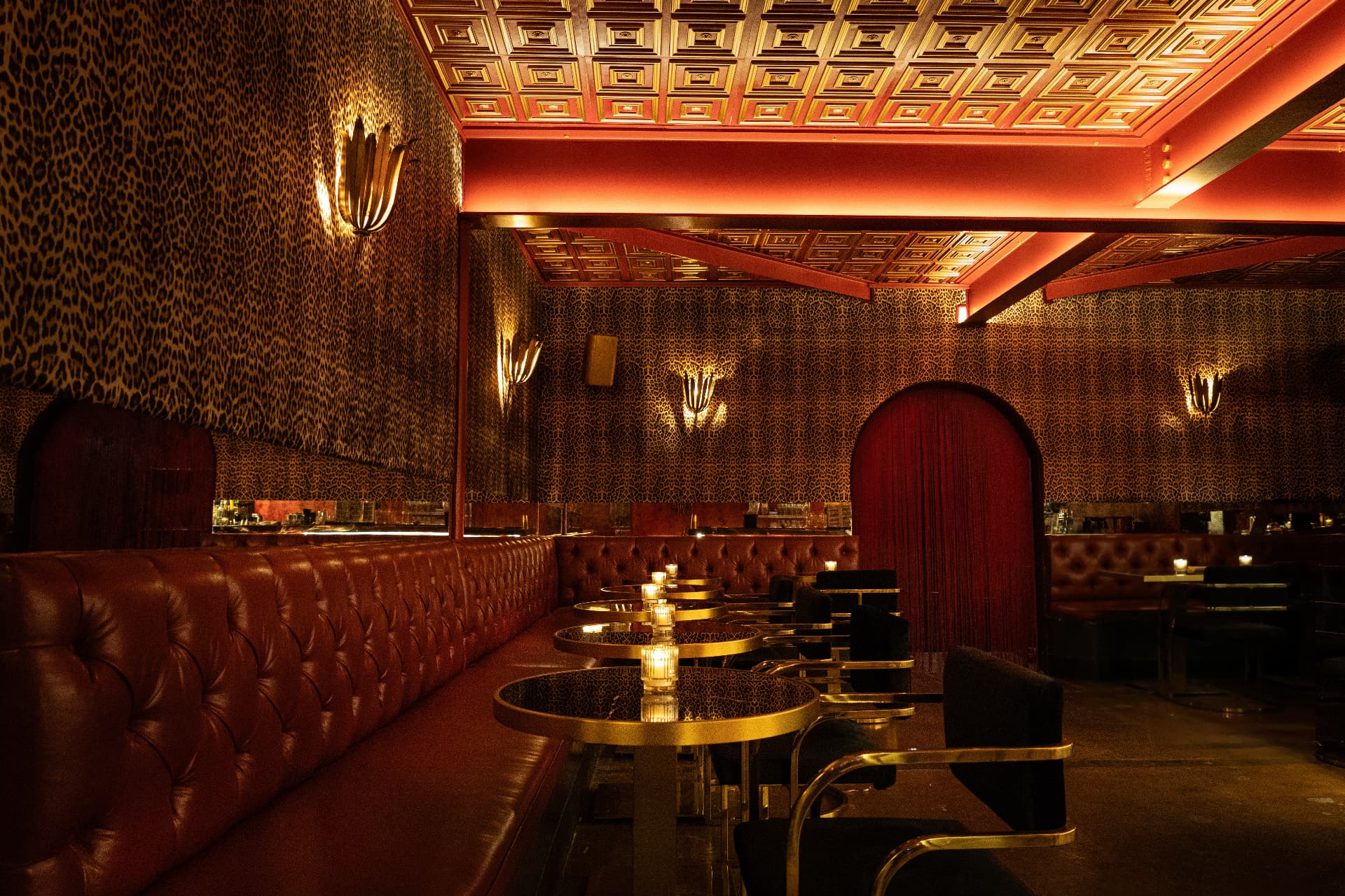 The Lounge at Jaguar Room with cheetah-print walls, tufted burgundy banquettes and brass sconces