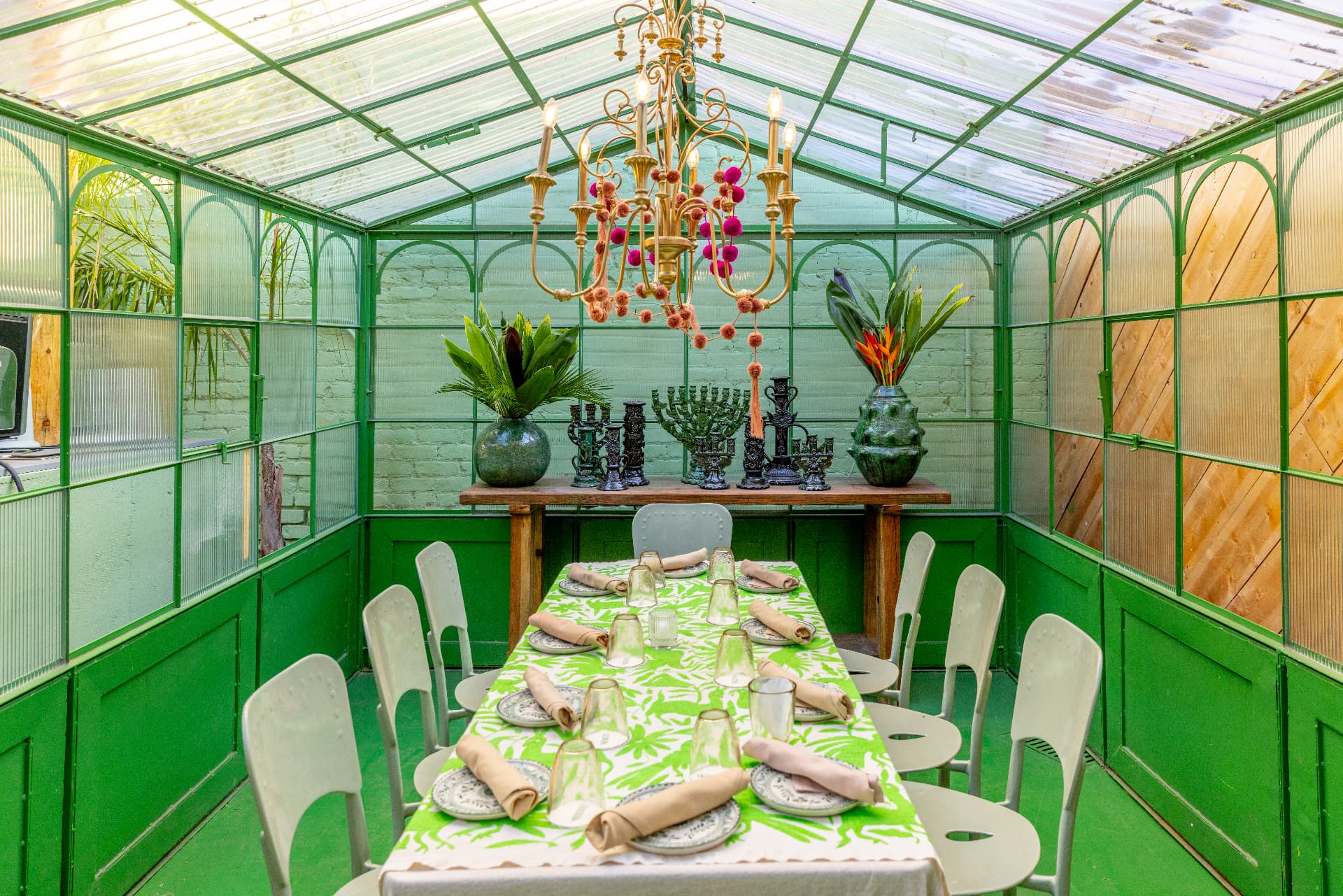 Casa Verde at Tacolina, a green-painted glasshouse solarium with a long set table and a brass chandelier