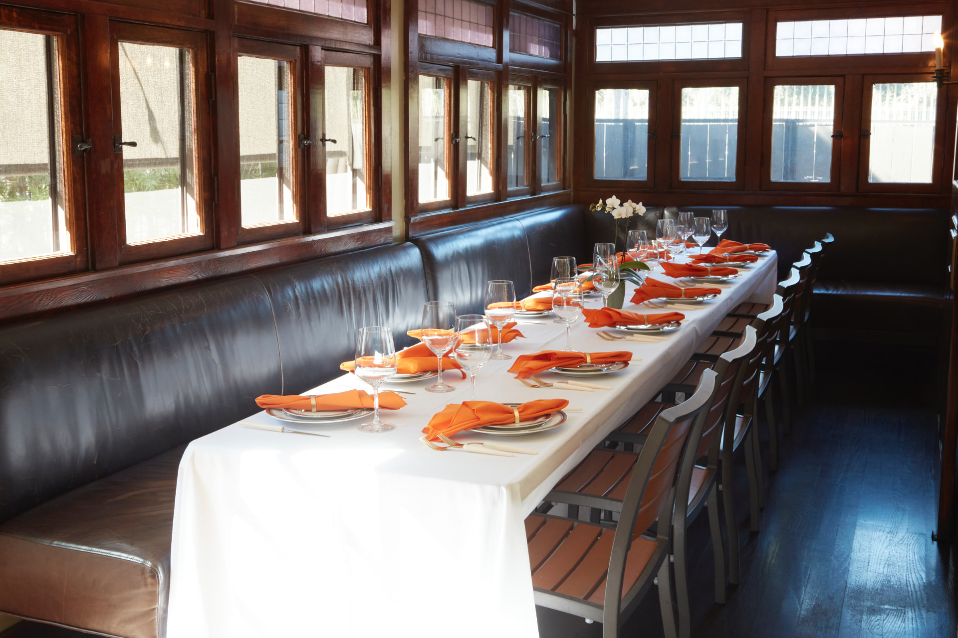 The Sunroom at The Raymond 1886 set with a long table and orange napkins