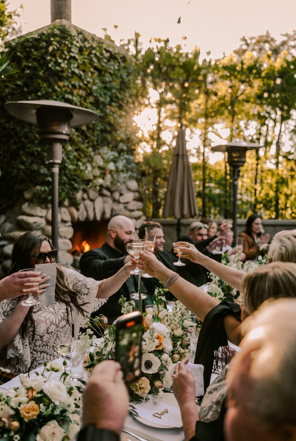 Wedding guests raising glasses on The Raymond 1886 Fireside Terrace